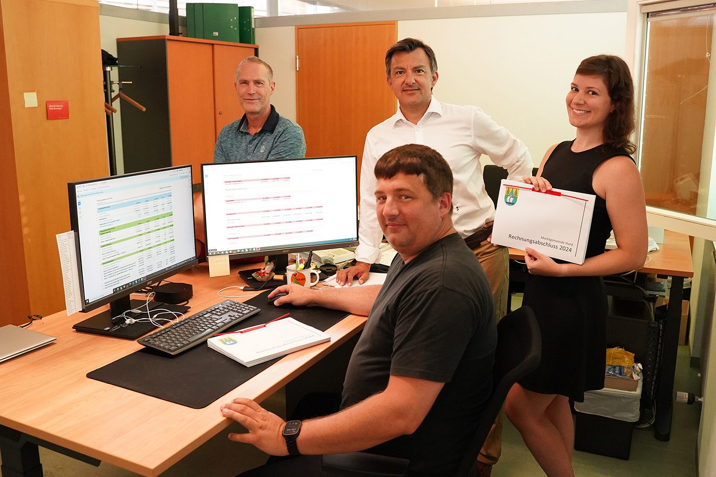 Bgm. Staudinger mit 3 Mitarbeitenden der Finanzabteilung in einem Büro. Eine Mitarbeiterin hält den Rechnungsabschluss 2024 in Händen.