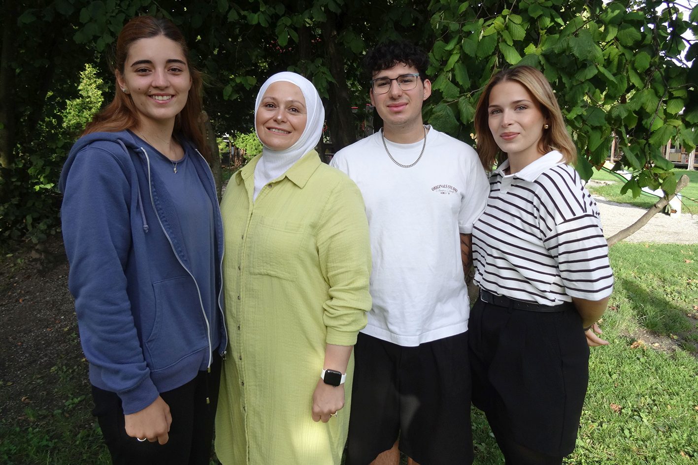Drei Kindergärtnerinnen und ein Kindergärtner stehen lächelnd vor einem Baum.