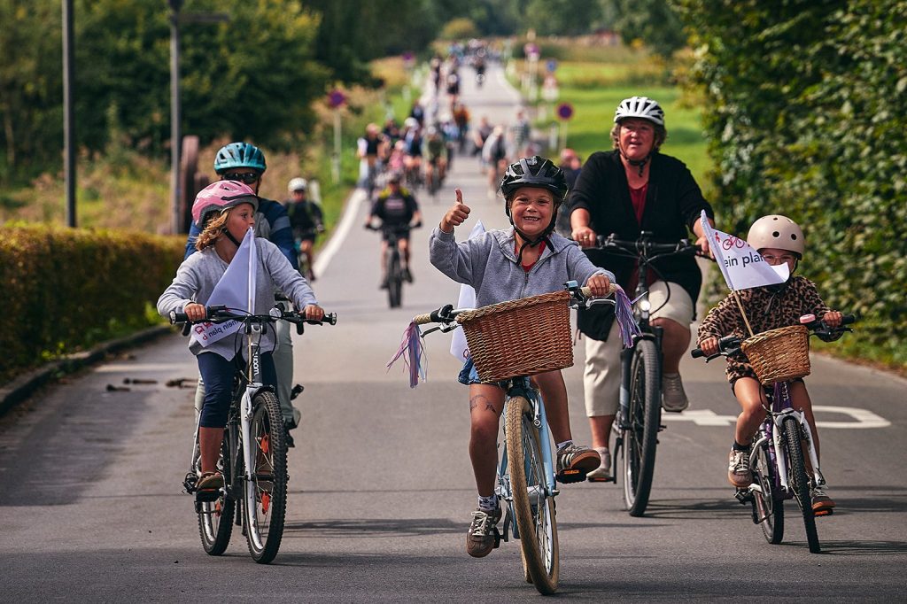 Eine Gruppe von Kindern und Erwachsenen auf Fahrrädern lächeln in die Kamera.