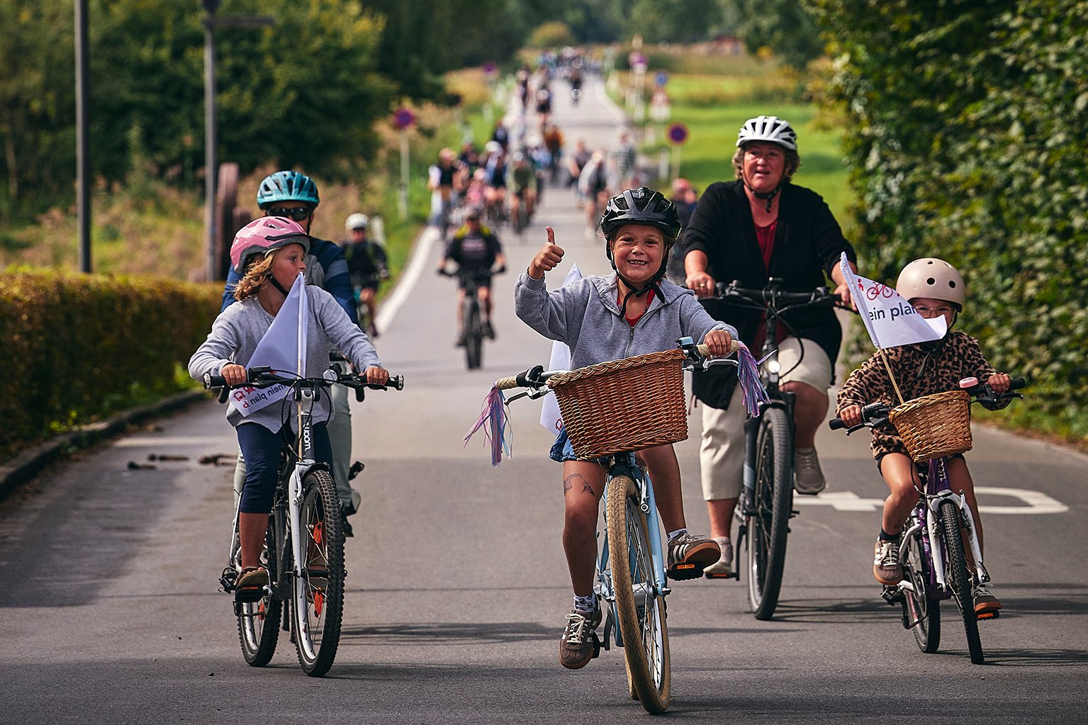 Eine Gruppe von Kindern und Erwachsenen auf Fahrrädern lächeln in die Kamera.
