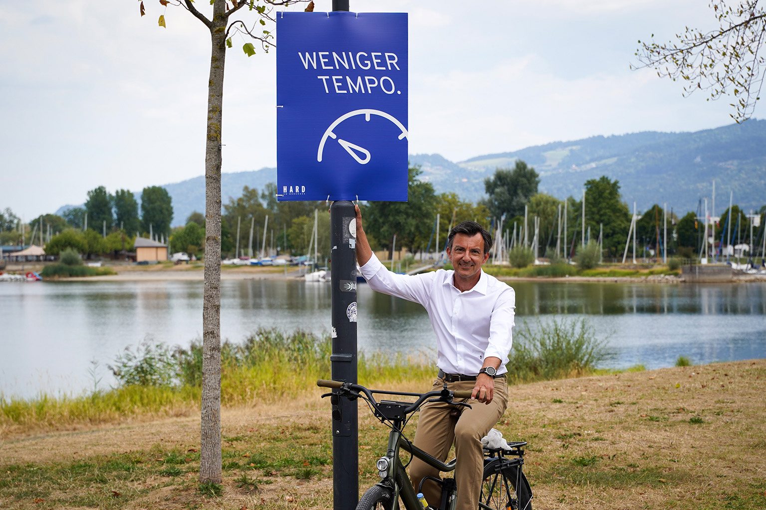 Bürgermeister Martin Staudinger auf dem Fahrrad vor einem Plakat mit der Aufschrift 