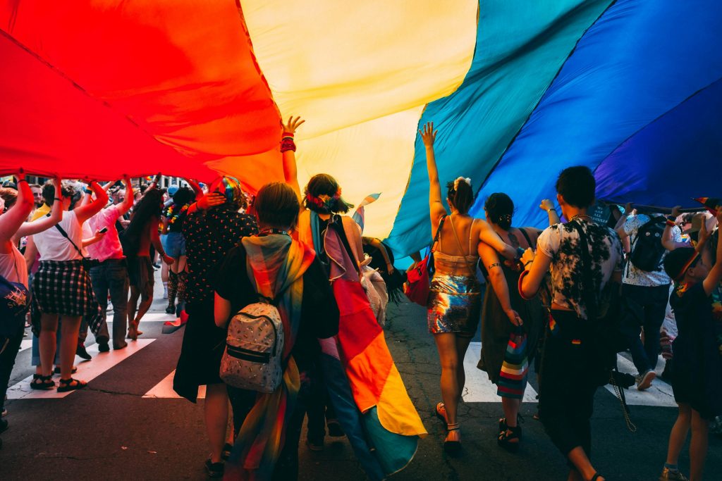 Junge Erwachsene unter einer Regenbogenfahne