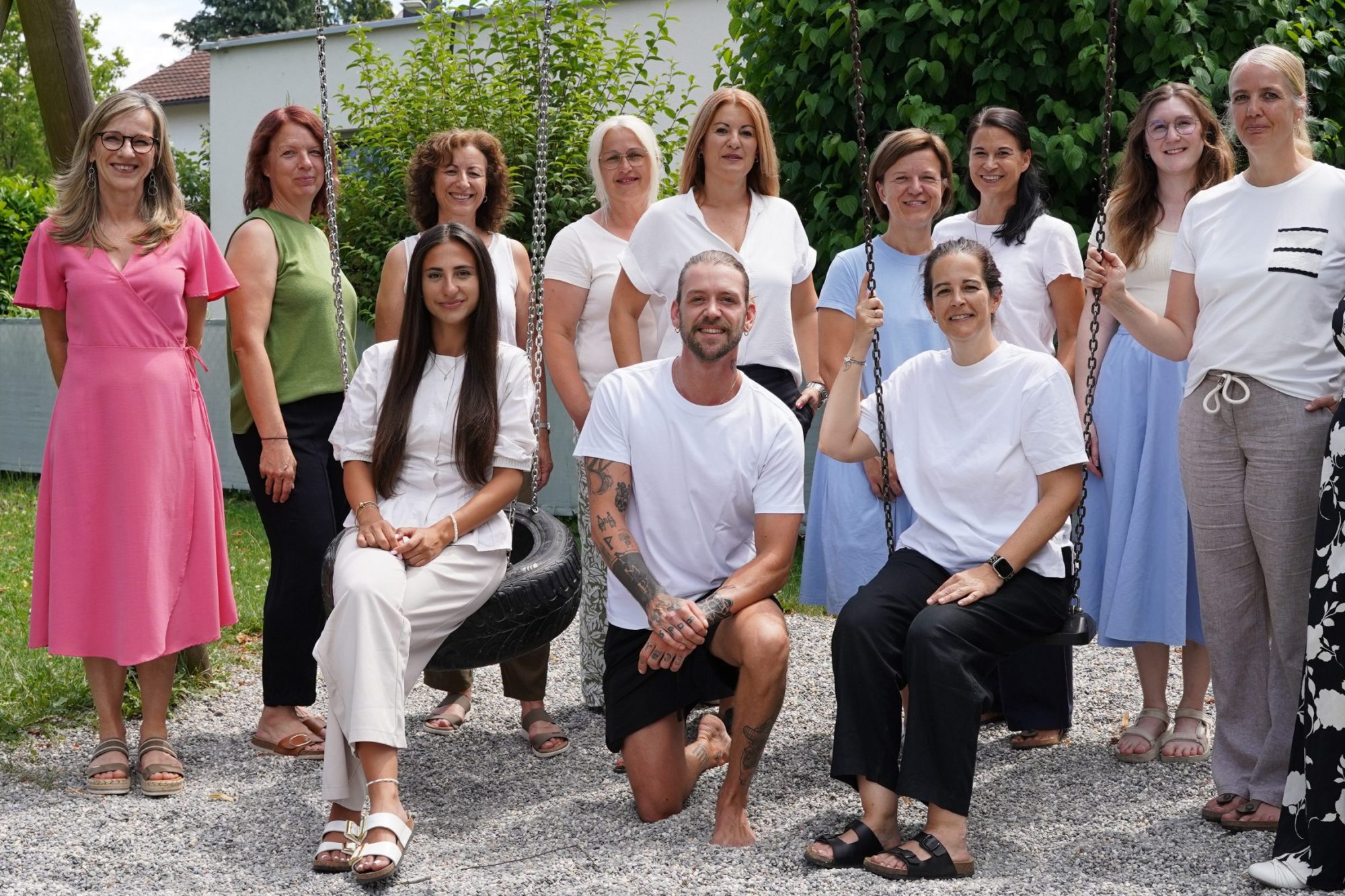 Teamfoto des Kindergartens Wallstraße: Die Mitarbeitenden posieren lächelnd an einem Schaukelgerüst im Freien.