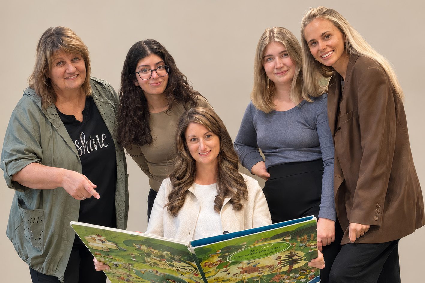 Das Team der Kleinkindbetreuung In der Wirke: Fünf Frauen posieren lächelnd mit einem großen Bilderbuch.