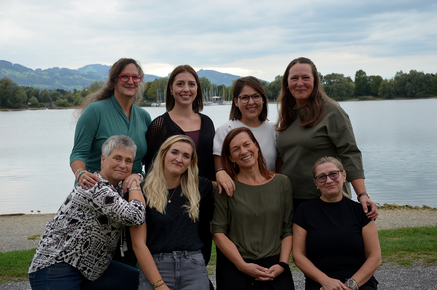 Gruppenfoto des Teams des Kindergarten Hölzele Naturhaus am Seeufer vor Bergkulisse.