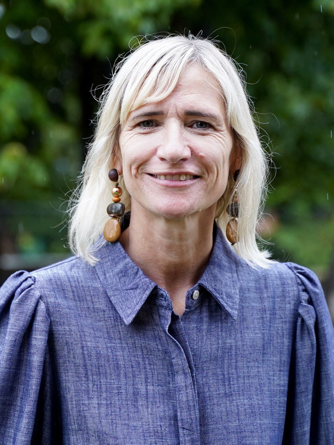 Porträt der Leiterin des Kindergarten Falkenweg Sandra Weinhofer-Nenning in blauer Bluse vor grünem Hintergrund.